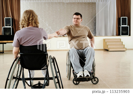 Mature man and unrecognizable woman in wheelchairs practicing dance in modern spacious studio Mature man and unrecognizable woman in wheelchairs practicing dance in modern spacious studio 113235903