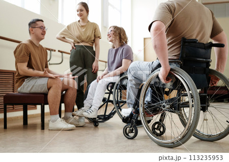 Low angle view selective focus shot of wheelchair dancers and their partners relaxing and chatting during break 113235953
