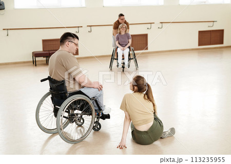 High angle view of man and woman in wheelchairs and their dance partners having break during practice High angle view of man and woman in wheelchairs and their dance partners having break during practice 113235955