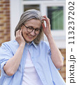 An older woman wearing glasses and a blue shirt. 113237202