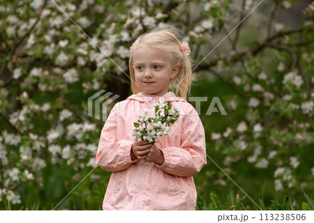 Portrait of thinkful little caucasian girl with spring floral garden in sunny day with flowering branch. 113238506