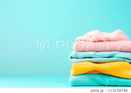 Stack of clean towels in laundry wicker basket on blue background. The towels showcasing their soft and fluffy textures Stack of clean towels in laundry wicker basket on blue background. The towels showcasing their soft and fluffy textures 113238746