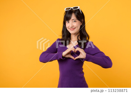 Celebrating Valentine's Day with joy, a young lady in a purple sweater sends a loving hand gesture, radiating positivity and romantic emotions. 113238871