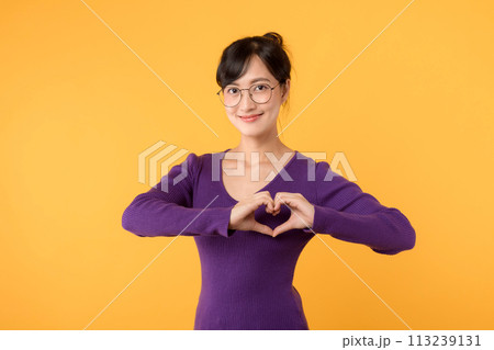 Portrait of an attractive and confident female model, her hand forming a heart shape, symbolizing love and happiness on Valentine's Day. Portrait of an attractive and confident female model, her hand forming a heart shape, symbolizing love and happiness on Valentine's Day. 113239131