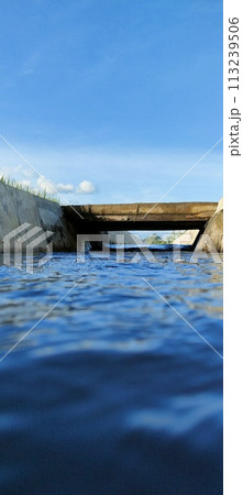 Small river on the edge of rice fields during the day 113239506