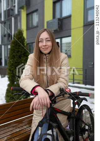 Woman Sitting on a Bench Next to a Bike 113240042