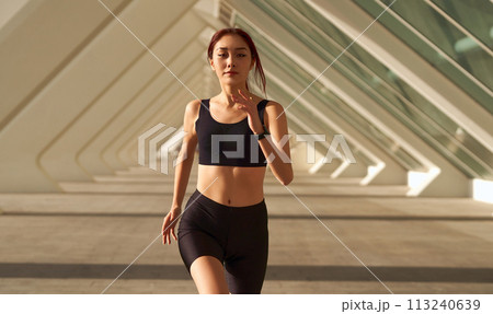 Close up of woman in sportswear is jogging around the city in early morning. Reaching the goal 113240639