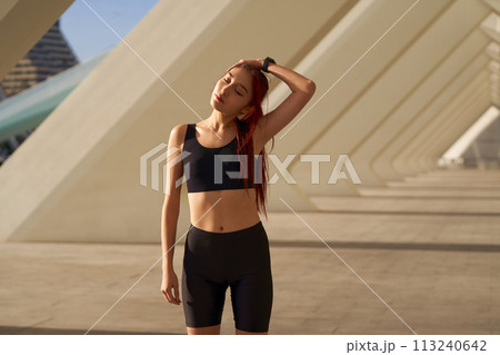 Sporty woman does warm-up exercises in morning before running training outside. Healthy fitness 113240642