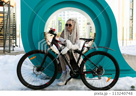 Woman Sitting on Bench Next to Bike 113240748