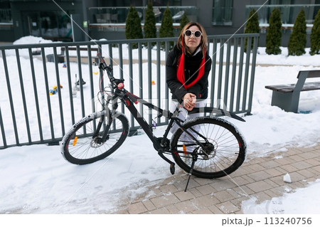 A woman rented a bicycle to ride around the city in winter. 113240756