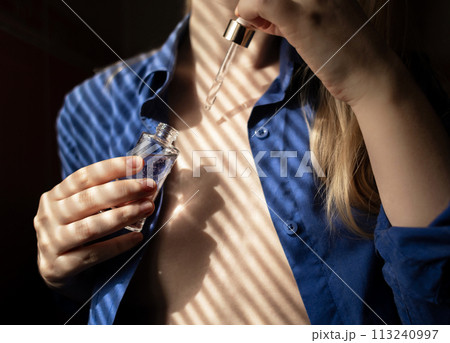Breast serum. The girl shows her cleavage, which she will take care of with collagen, peptides, hyaluronic acid, glycerin, antioxidants, vitamins, and retinol. Prevention of breast stretch marks Breast serum. The girl shows her cleavage, which she will take care of with collagen, peptides, hyaluronic acid, glycerin, antioxidants, vitamins, and retinol. Prevention of breast stretch marks 113240997