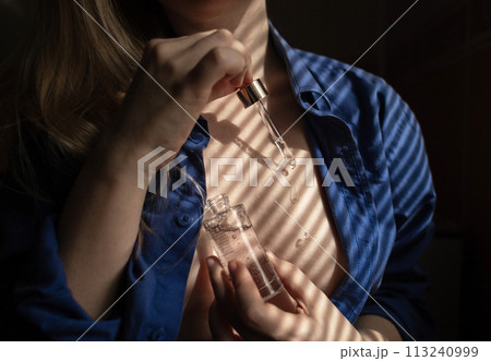 Breast serum. The girl shows her cleavage, which she will take care of with collagen, peptides, hyaluronic acid, glycerin, antioxidants, vitamins, and retinol. Prevention of breast stretch marks Breast serum. The girl shows her cleavage, which she will take care of with collagen, peptides, hyaluronic acid, glycerin, antioxidants, vitamins, and retinol. Prevention of breast stretch marks 113240999