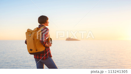 Young woman hiking on rocky beach in Spain, Benidorm. Watching the choppy sea and the bay. traveler enjoying freedom in serene nature landscape 113241305