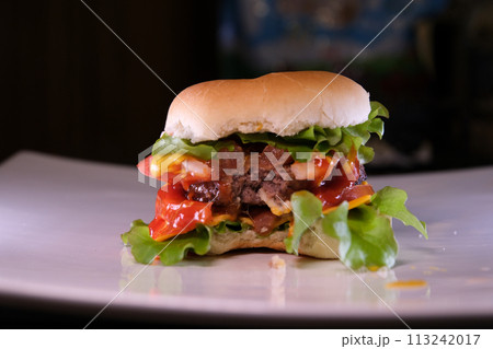 Video overhead shot of bitten burger in bun on white plate with copy space. tasty hot homemade fast food meal. 113242017