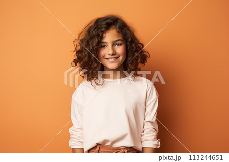 A young girl with curly hair is smiling and wearing a white shirt 113244651