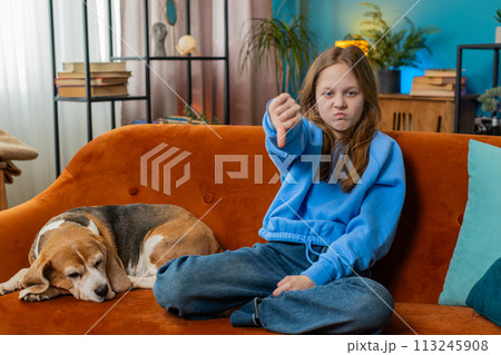 Upset child girl kid showing thumbs down sign gesture, expressing discontent disapproval dislike 113245908