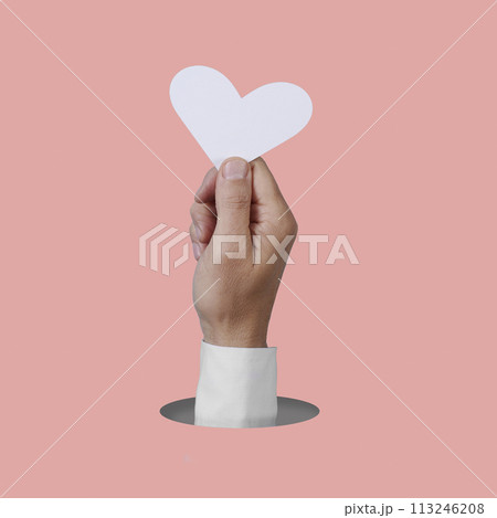 man holding a white heart popping out of a hole 113246208