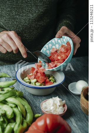 man prepares a spanish salad with broad beans man prepares a spanish salad with broad beans 113246211