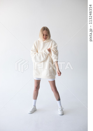 Beautiful blonde woman posing in white hoodie and leggings posing against white background Beautiful blonde woman posing in white hoodie and leggings posing against white background 113246354