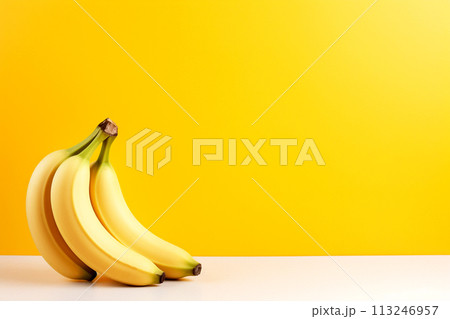 three ripe bananas against a yellow background, perfect for tropical fruit-themed designs with ample copy space. ideal for promoting tropical flavors or healthy eating habits 113246957