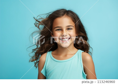 A young girl with long hair is smiling and wearing a blue tank top 113246960