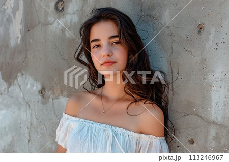 A woman with long hair is standing in front of a wall 113246967