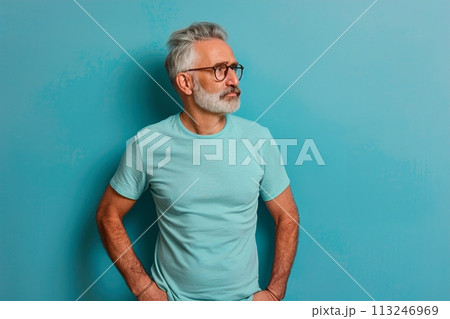 A man in a blue shirt stands in front of a blue wall 113246969