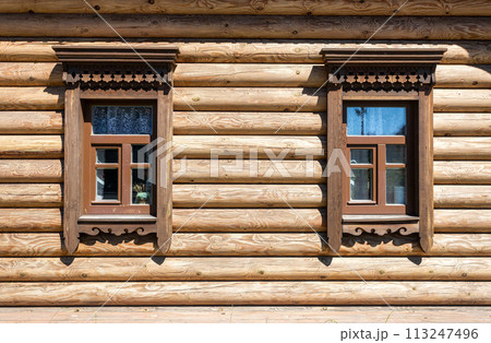Windows of wooden house decorated with wooden carvings, platbands, wooden lace ornament Windows of wooden house decorated with wooden carvings, platbands, wooden lace ornament 113247496