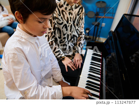 Confident talented teenage musician plays piano forte, creates music and song composes a melody during music lesson Confident talented teenage musician plays piano forte, creates music and song composes a melody during music lesson 113247877