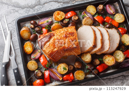 Honey baked pork loin with potatoes, onions, bell peppers and mushrooms close-up on a baking sheet. Horizontal top view Honey baked pork loin with potatoes, onions, bell peppers and mushrooms close-up on a baking sheet. Horizontal top view 113247929