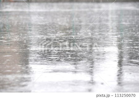 アスファルトの道路の水たまりに打つつける雨の水紋 アスファルトの道路の水たまりに打つつける雨の水紋 113250070