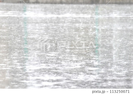 アスファルトの道路の水たまりに打つつける雨の水紋 アスファルトの道路の水たまりに打つつける雨の水紋 113250071
