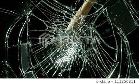 Freeze motion of glass-breaking hammer, shattering against black background 113250811