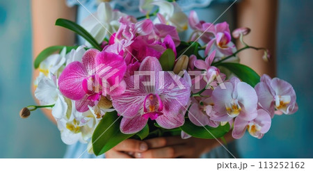 A woman poised hands present a stunning bouquet of orchids A woman poised hands present a stunning bouquet of orchids 113252162