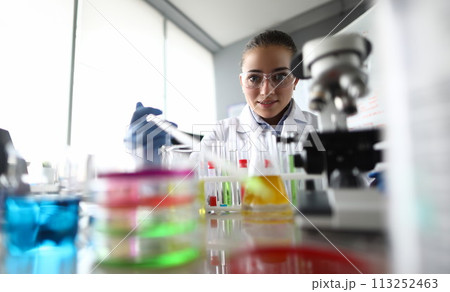 Assistant pouring liquid into flask 113252463