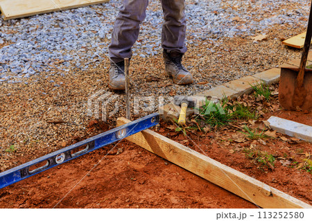 Formwork for pouring of concrete on foundation is produced by workers using templates removable timbers 113252580