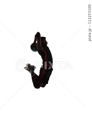 Dynamic image of concentrated young man, basketball player in motion, throwing ball in jump, playing isolated on white background. Silhouette 113253100