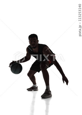 Silhouette of young concentrated young man, basketball player in motion during game, dribbling ball isolated on white background Silhouette of young concentrated young man, basketball player in motion during game, dribbling ball isolated on white background 113253140