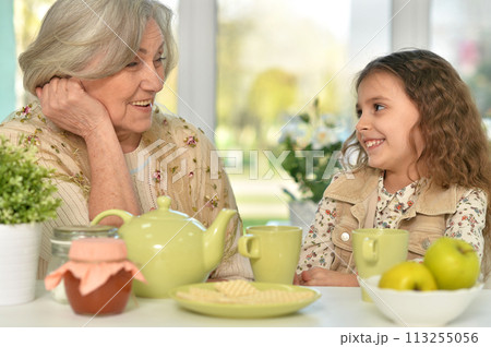 Old woman with a young girl drinking tea on the table Old woman with a young girl drinking tea on the table 113255056