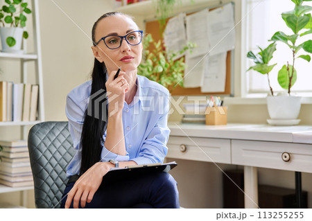 Portrait of female psychotherapist with clipboard at workplace in office Portrait of female psychotherapist with clipboard at workplace in office 113255255