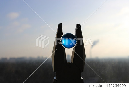 Blue translucent sphere in pliers on the background of a blurred cityscape as a metaphoric symbol of planet ecological issues Blue translucent sphere in pliers on the background of a blurred cityscape as a metaphoric symbol of planet ecological issues 113256099