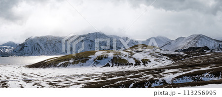 Season change in the Icelandic highlands.  Colorful Landmannalaugar mountains under snow cover in autumn. Frostastadavatn lake at the foot of the mountains. 113256995