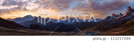Sun glow in evening hazy sky. Mountain panoramic peaceful view from Giau Pass. Sun glow in evening hazy sky. Mountain panoramic peaceful view from Giau Pass. 113257260