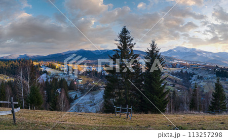 Late autumn mountain pre sunset scene with snow covered tops in far. Picturesque traveling, seasonal, nature and countryside beauty concept scene. Carpathians, Ukraine. Late autumn mountain pre sunset scene with snow covered tops in far. Picturesque traveling, seasonal, nature and countryside beauty concept scene. Carpathians, Ukraine. 113257298