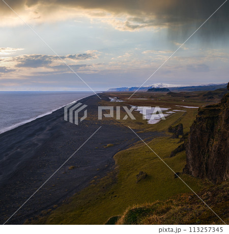 Picturesque autumn evening view to endless ocean black volcanic sand beach from Dyrholaey Cape Viewpoint, Vik, South Iceland. Picturesque autumn evening view to endless ocean black volcanic sand beach from Dyrholaey Cape Viewpoint, Vik, South Iceland. 113257345