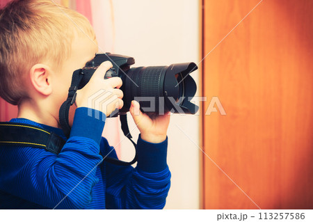 Kid playing with big professional digital camera 113257586