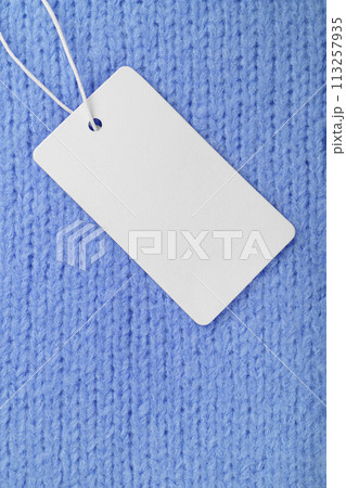 Template of blank clothing label, price tag on blue knitted sweater background Template of blank clothing label, price tag on blue knitted sweater background 113257935