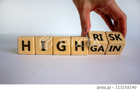 Cube form the expression 'high risk, high gain'. Male hand. Beautiful white background. Business concept, copy space. Cube form the expression 'high risk, high gain'. Male hand. Beautiful white background. Business concept, copy space. 113258140