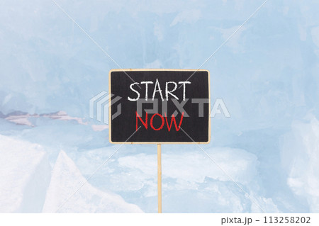 Start now symbol. Concept words Start now on beautiful yellow black blackboard. Beautiful blue ice background. Business marketing, motivational start now concept. Copy space. 113258202
