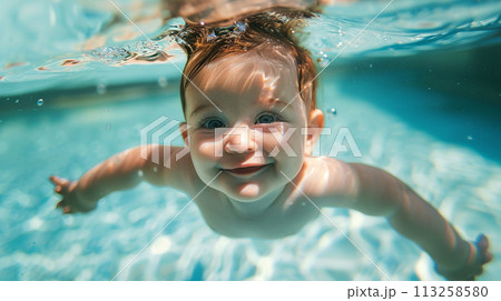 A smiling baby swims underwater in a pool 113258580